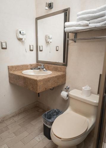 a bathroom with a sink and a toilet and a mirror at Hotel Madrid in Tuxtla Gutiérrez