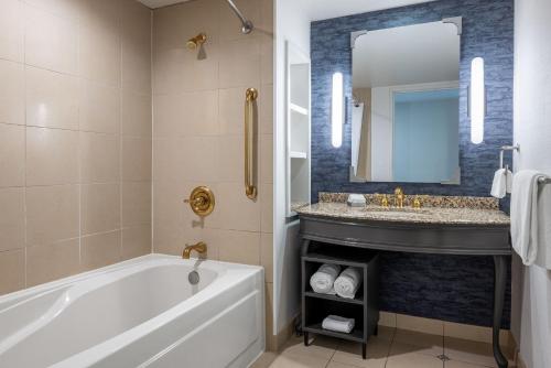 a bathroom with a tub and a sink and a mirror at Harrah's Metropolis Hotel & Casino - A Caesars Rewards Destination in Metropolis