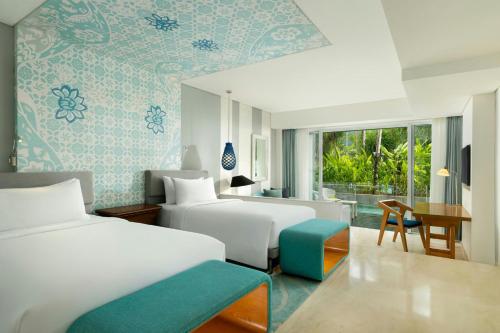 a hotel room with two beds and a desk at Le Meridien Bali Jimbaran in Jimbaran