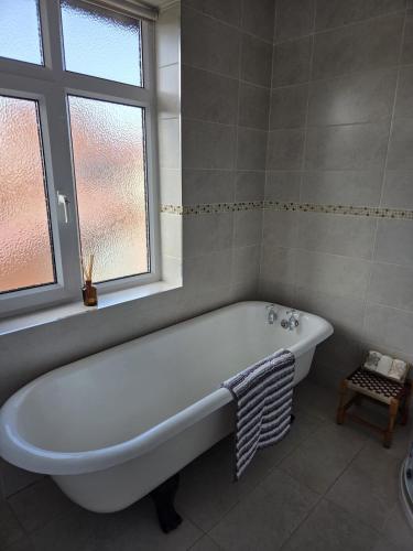 a white bath tub in a bathroom with a window at Flown The Nest in Bridlington