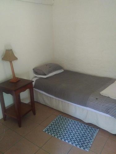 a small room with a bed and a table with a lamp at Isikhoma-Khoma in Hilton