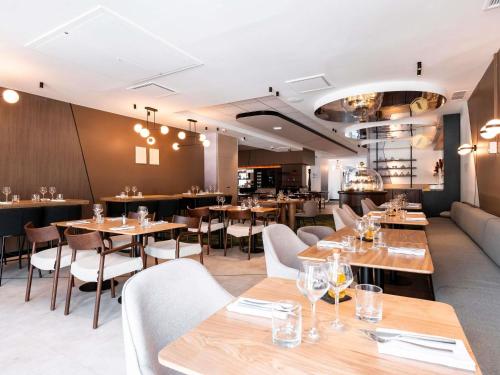 a restaurant with wooden tables and white chairs at Novotel Grenoble Centre in Grenoble