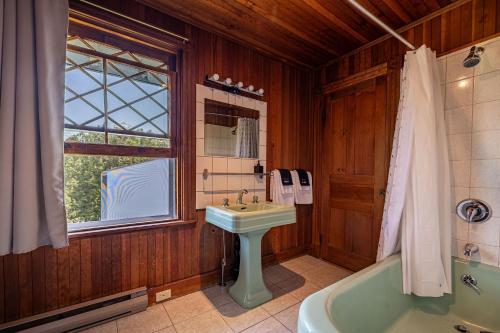 a bathroom with a sink and a tub and a window at Auberge Les Sources in La Malbaie