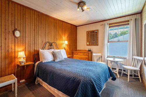 a bedroom with a bed and a table and a window at Auberge Les Sources in La Malbaie