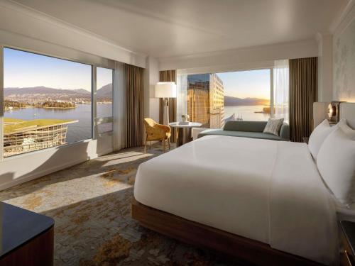 a bedroom with a large bed and a large window at Fairmont Waterfront in Vancouver