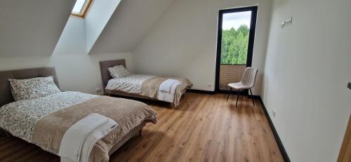a bedroom with two beds and a window at Dom Na Chwilę in Brzozowa