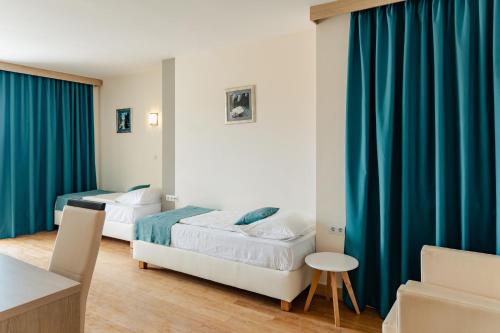 two beds in a room with blue curtains at Hotel Villa MiraMar in Omiš