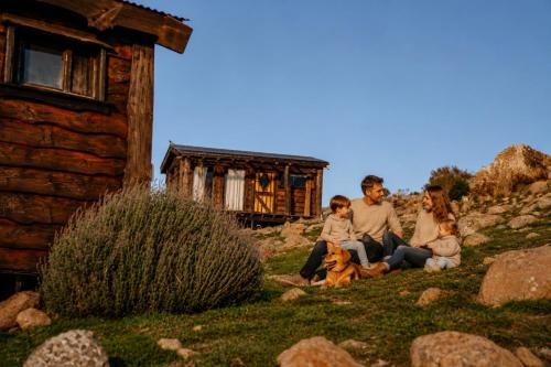 a family sitting outside of a cabin with their dog at Valle de la Luna in Tandil