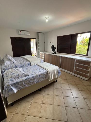 a bedroom with two beds and a large window at Casa Brisa do Mar in Pipa