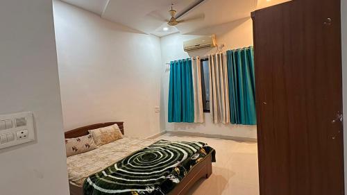 a small bedroom with a bed and green curtains at The Golden palace in Paratwāda