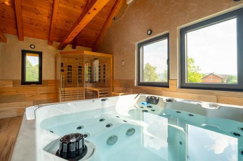 a large white tub in a room with windows at Kuća za odmor Vrata Papuka in Pakrac