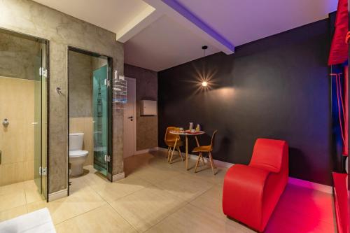 a living room with a red chair and a table at Dreams Motel (Adult Only) in Fortaleza