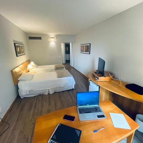 a room with a bed and a desk with a laptop at StudioTriplo Superior Completo 608- Casal e Solteiro ou 3 Solteiros in Barueri