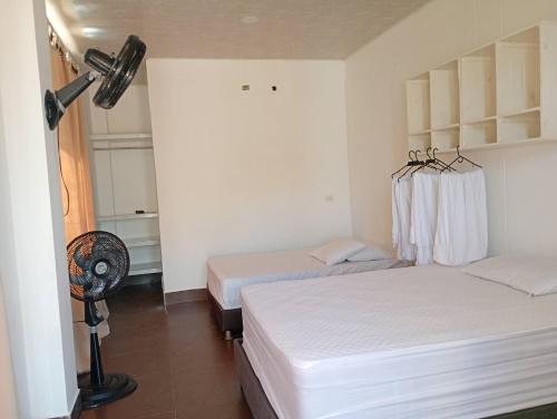 a hotel room with two beds and a fan at Astilleros Santa Veronica in Santa Verónica