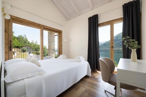 a bedroom with a bed and a desk and windows at Perla di Mergozzo 2 in Mergozzo