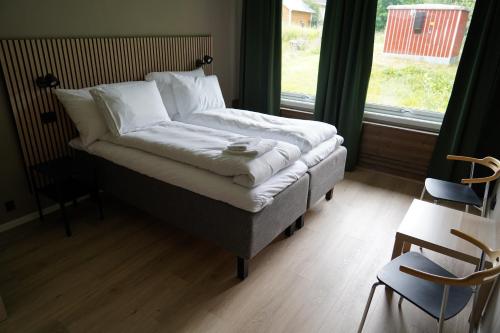 a bedroom with a bed with white sheets and a window at Birtavarre Aurora Adventures in Birtavarre