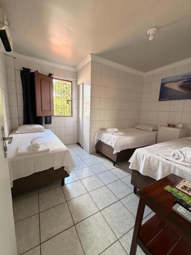 a room with two beds and a table in it at Hospedaria Maranhense in São Luís