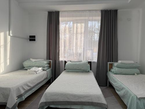 a room with two beds and a window at Luxe Hotel in Kazarman
