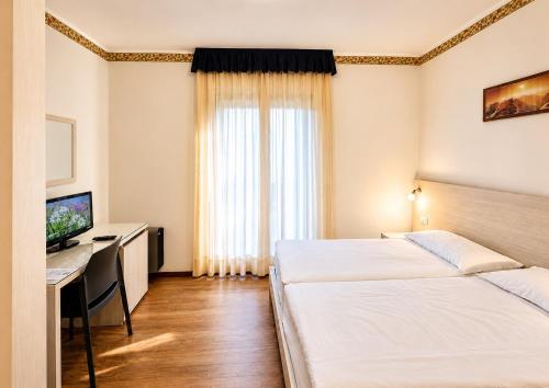 a hotel room with two beds and a desk with a computer at Hotel International in Tarvisio