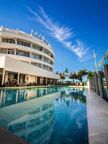 a hotel with a swimming pool in front of a building at Marambaia Hotel e Convenções in Balneário Camboriú