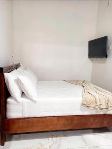 a bed with white sheets and a tv on a wall at Hotel Boutique Porvenir Real in Charalá