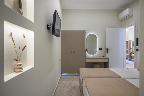 a bedroom with white walls and a bed and a mirror at Argiri Apartments & Suites in Georgioupolis