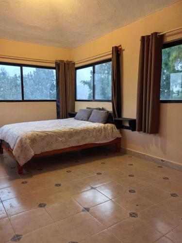 a bedroom with a bed in a room with windows at Casa Cariño in San Cristóbal de Las Casas