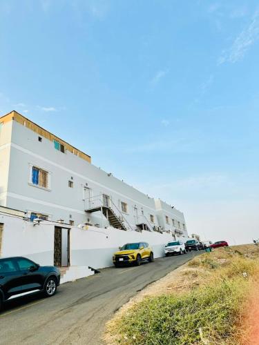 a white building with cars parked in front of it at شقق ارين المصيف للشقق المخدومة in Al Hada