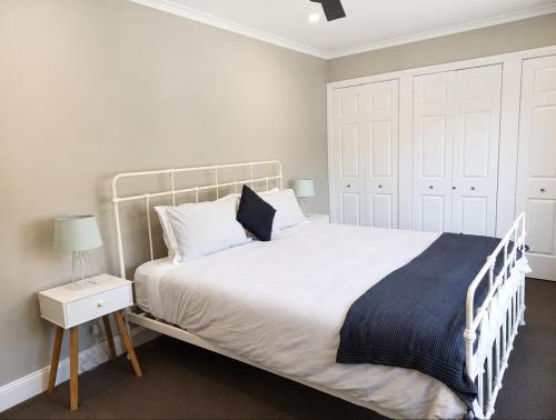 a bedroom with a large white bed with a night stand at The River House - Wisemans Ferry in Wisemans Ferry