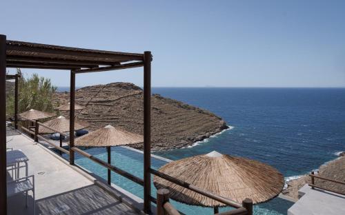 a row of straw umbrellas and the ocean at Off the beaten path! Maisonette & Pool in Kithnos