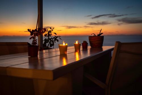 four candles sitting on a table with a sunset in the background at Off the beaten path! Maisonette & Pool in Kithnos