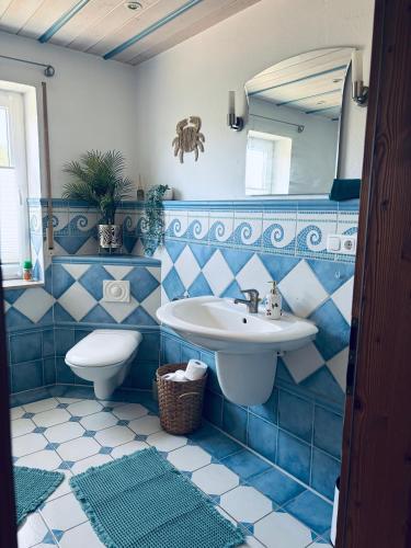 a blue tiled bathroom with a sink and a toilet at Ferienapartment Naturblick in Hausen