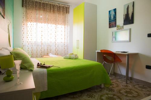 ポルトパーロにあるB&B Giosyの緑のベッド、デスク、窓が備わるベッドルーム1室が備わります。