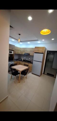a large kitchen with a table and a refrigerator at Location par nuitée in Oran