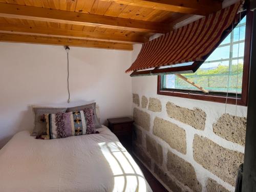 a bed in a room with a stone wall at The Hidalga's cozy house in Arafo