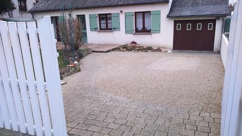 a white fence in front of a house with a driveway at L'écume du Cher in Bléré