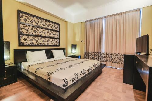 a bedroom with a bed and a flat screen tv at Rapo's Resort Hotel in Himare