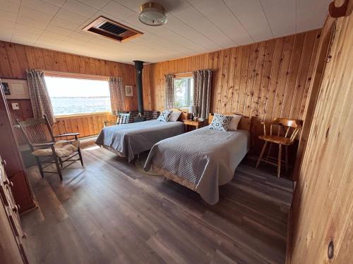 a bedroom with two beds and a table and chairs at Bob's Cabin at Wishart's Point Lodge in Neguac