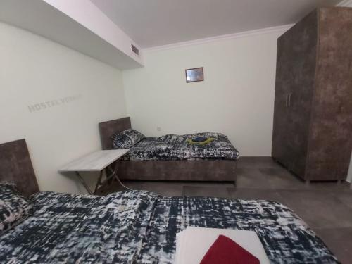 a room with two beds and a desk in it at Hostel VOYAGE in Batumi