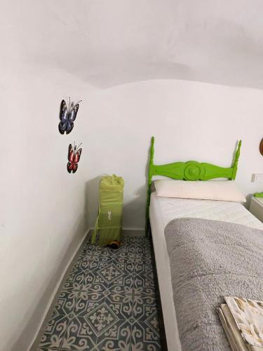 a bedroom with a bed with a green headboard and butterflies on the wall at Cueva mágica de Raspay in Raspay