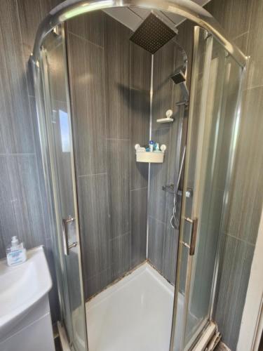 a shower with a glass door in a bathroom at Nad's Guest house in Motherwell
