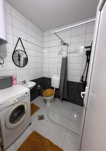 a bathroom with a washing machine and a toilet at Unik Apartment in Kosovo Polje