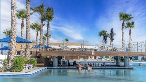 a pool with palm trees and people in the water at Encantame Velero Ground Floor, BeachFront in Playa Encanto
