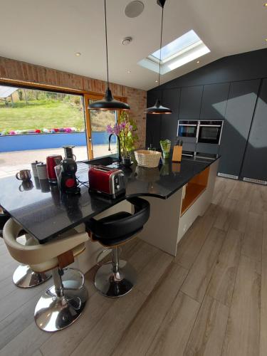 a kitchen with a black counter and some chairs at Golf Style in Lisdoonvarna