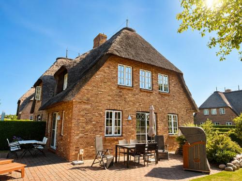 a large brick house with a thatched roof at Haus "Carla Marie" in Hedehusum
