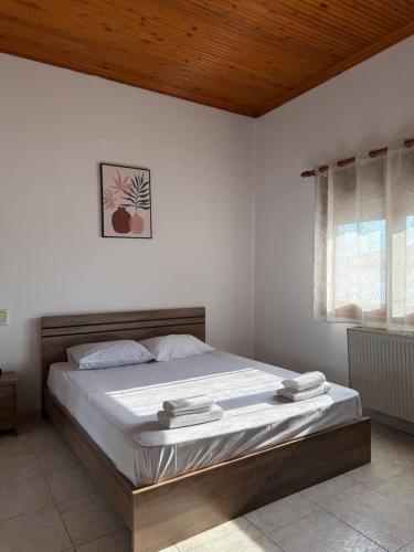 a bedroom with a bed with white sheets and a wooden ceiling at Maronia Villa in Maronia