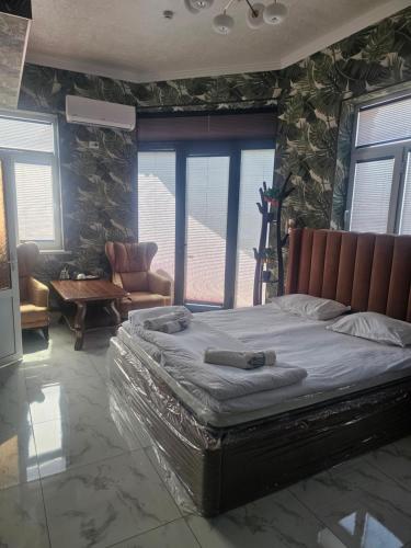 a bedroom with a large bed in a room with windows at Turg'unTown in Toshkent-Passajir Bekati