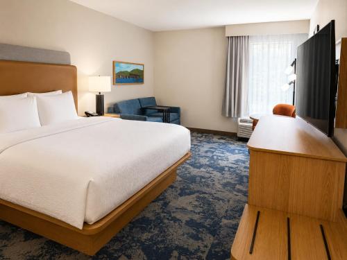 a hotel room with a large bed and a chair at Hampton Inn Cartersville in Cartersville