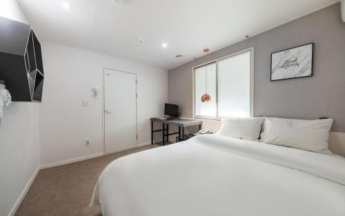 a white bedroom with a large bed and a window at Hotel AMY in Incheon