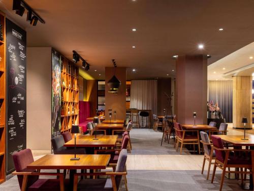 ein Restaurant mit Holztischen und -stühlen sowie Tischen und Tischplatten in der Unterkunft Mercure Gdynia Centrum in Gdynia